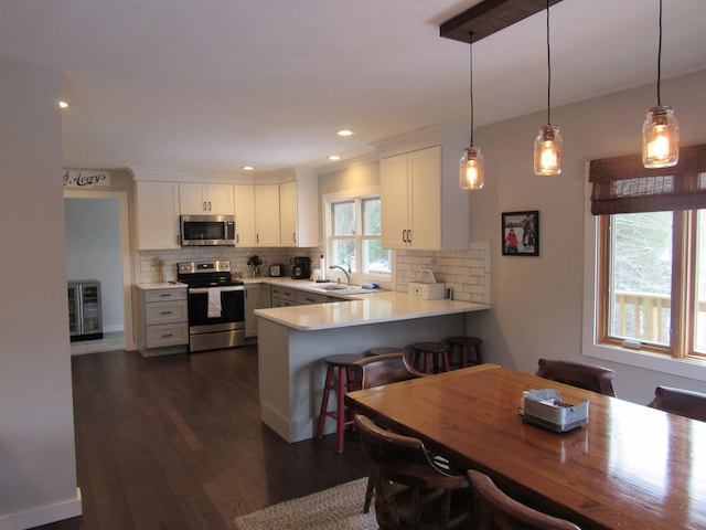 kitchen with decorative backsplash, a peninsula, white cabinetry, and stainless steel appliances