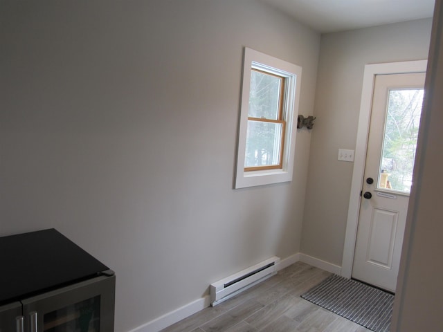 doorway featuring a baseboard radiator, baseboards, and light wood-style flooring