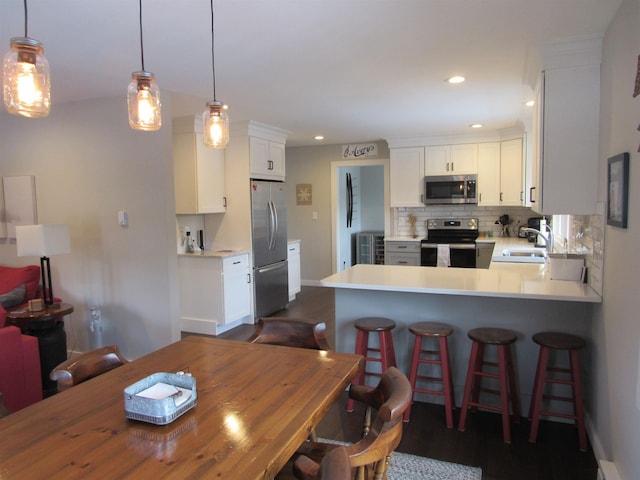 kitchen featuring a sink, tasteful backsplash, white cabinetry, appliances with stainless steel finishes, and light countertops