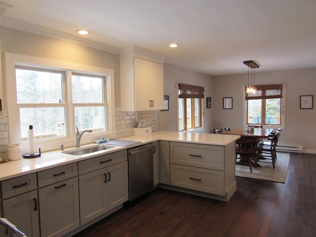 kitchen with a sink, dark wood finished floors, a peninsula, light countertops, and dishwasher