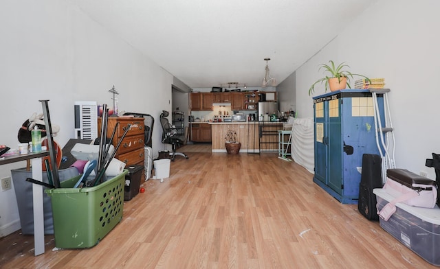 interior space with light countertops, a peninsula, freestanding refrigerator, light wood-style floors, and brown cabinetry