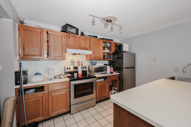 kitchen with under cabinet range hood, a sink, stainless steel appliances, light countertops, and light tile patterned floors