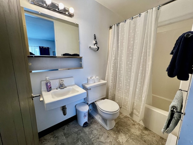 bathroom featuring toilet, baseboards, shower / bath combo with shower curtain, and a sink