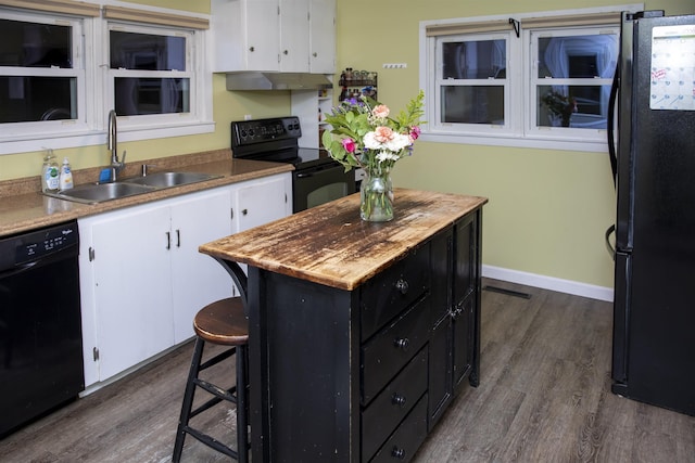 kitchen with white cabinetry, black appliances, dark cabinets, and a sink