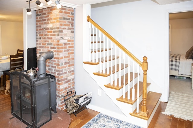 stairway featuring a wood stove and wood finished floors