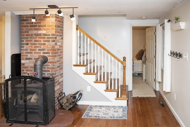 staircase featuring visible vents, a wood stove, wood finished floors, and baseboards