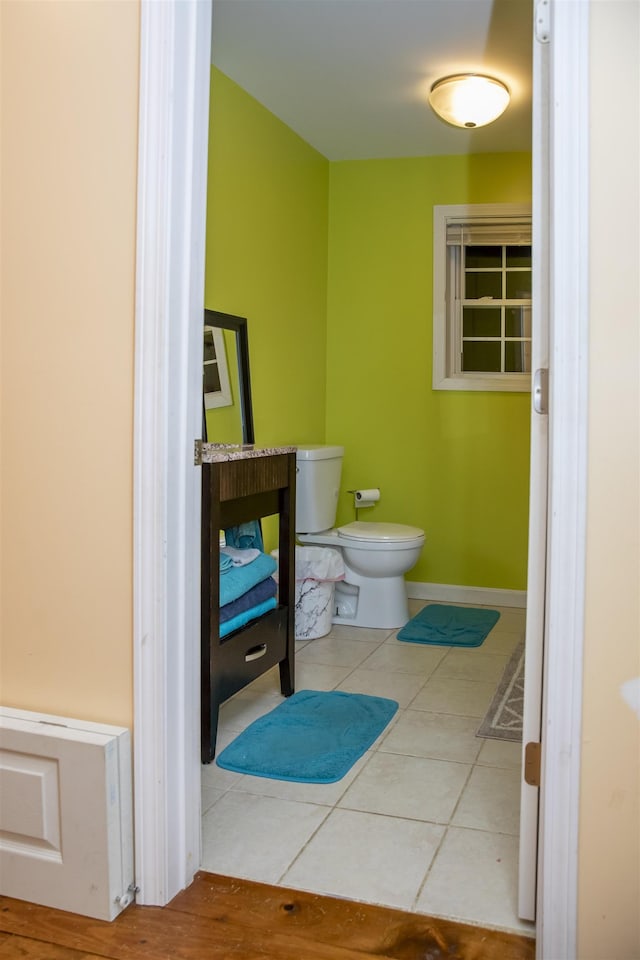 half bathroom with tile patterned floors, baseboards, and toilet