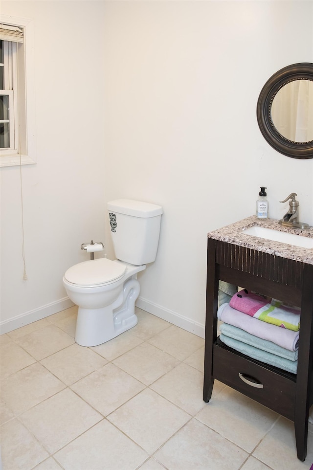 half bathroom featuring baseboards, toilet, vanity, and tile patterned flooring