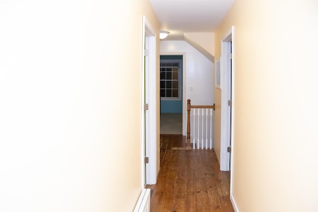 hall with dark wood finished floors, an upstairs landing, and vaulted ceiling