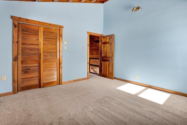 unfurnished bedroom with carpet, baseboards, and a towering ceiling