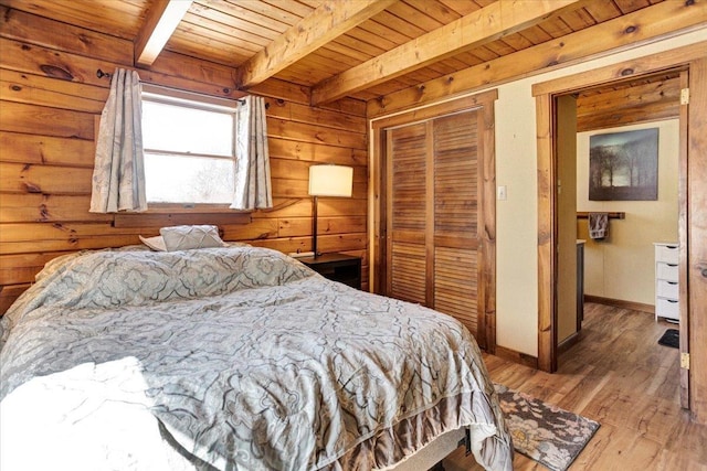 bedroom with light wood-type flooring, beam ceiling, a closet, wooden walls, and wood ceiling