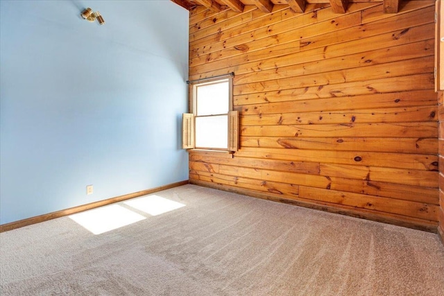 unfurnished room with light carpet, beamed ceiling, baseboards, and wooden walls