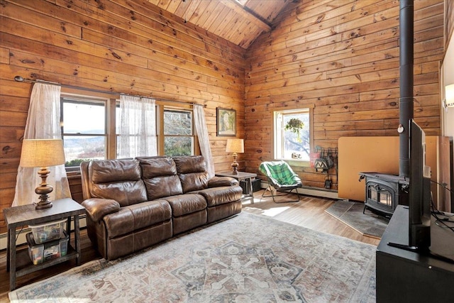 living room featuring wood finished floors, high vaulted ceiling, a wood stove, wood walls, and wooden ceiling