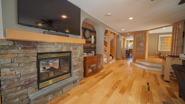 living room featuring stairway, baseboards, light wood-style flooring, recessed lighting, and a stone fireplace