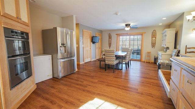 kitchen with stainless steel refrigerator with ice dispenser, light wood-style floors, double oven, light countertops, and ceiling fan