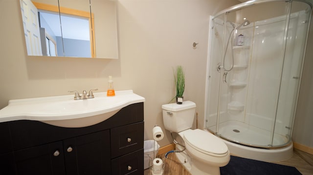 bathroom with baseboards, vanity, toilet, and a shower stall