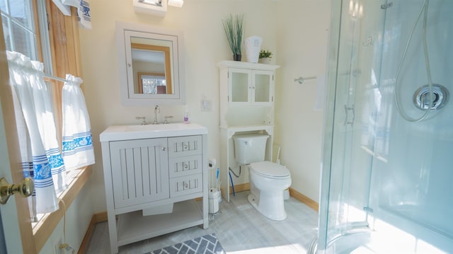 full bathroom with baseboards, vanity, a shower stall, and toilet