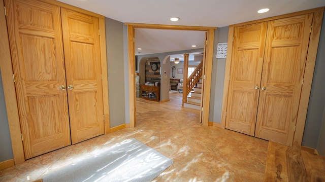 corridor featuring arched walkways, recessed lighting, stairs, and baseboards