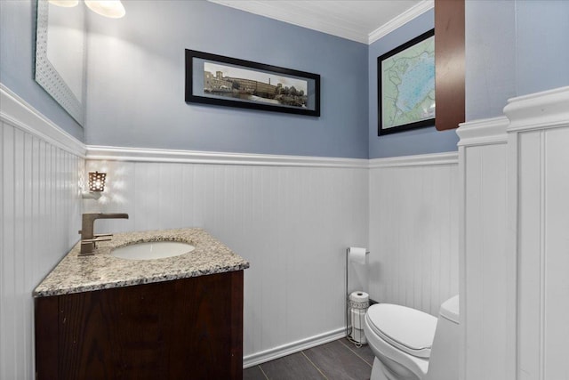 bathroom with a wainscoted wall, crown molding, toilet, and vanity