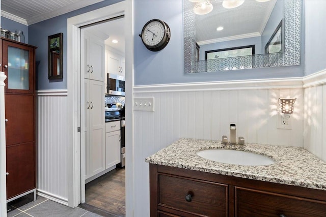 bathroom with vanity, crown molding, and wainscoting