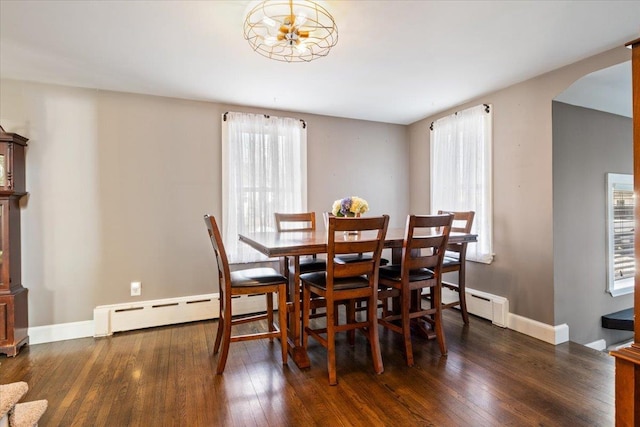 dining area with arched walkways, baseboard heating, baseboards, and hardwood / wood-style floors