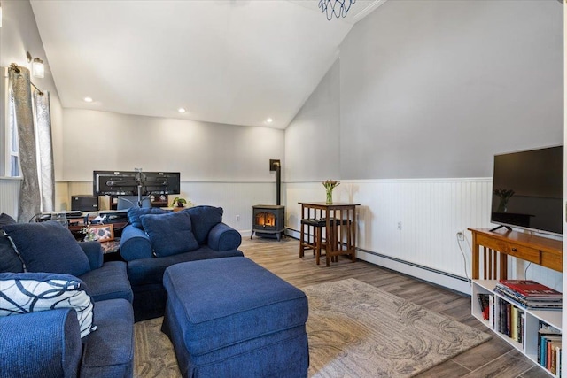 living area with a wainscoted wall, baseboard heating, recessed lighting, a wood stove, and wood finished floors