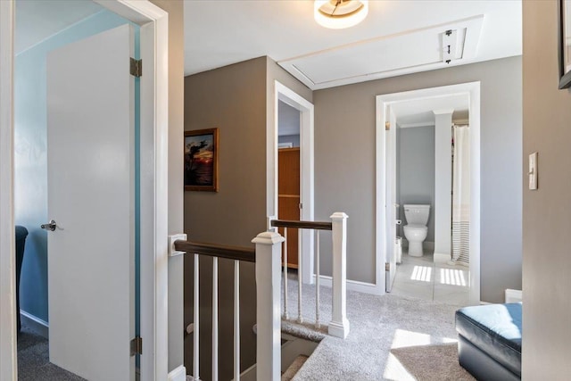 corridor with an upstairs landing, baseboards, and carpet floors