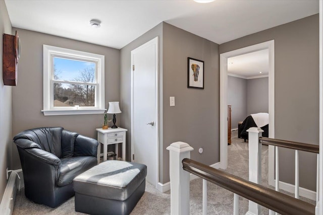 sitting room featuring baseboards, a baseboard heating unit, an upstairs landing, and light carpet