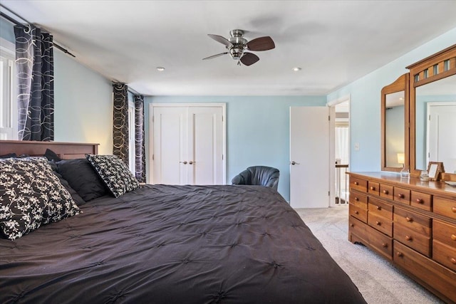 bedroom featuring a closet, light colored carpet, and a ceiling fan