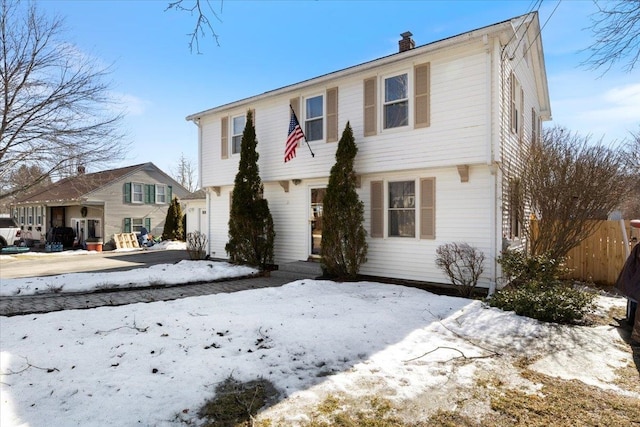 colonial-style house with a chimney and fence