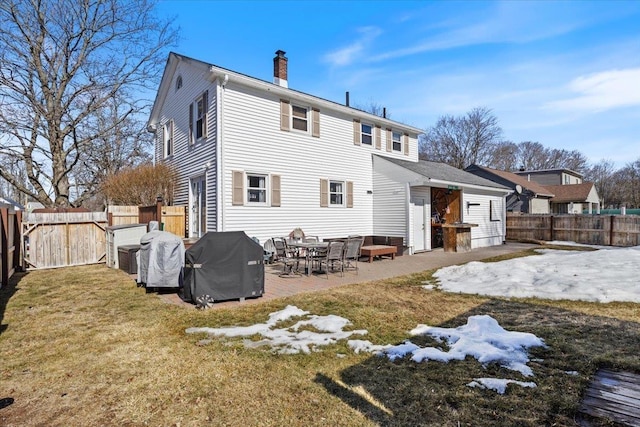 back of house featuring a patio area, a lawn, a fenced backyard, and a chimney