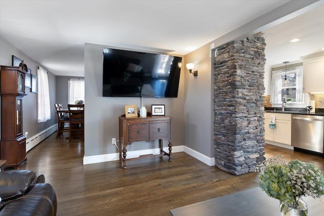 living area with a baseboard radiator, baseboards, and dark wood-style flooring