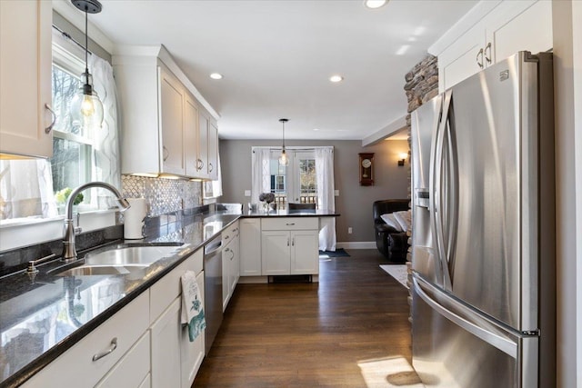 kitchen featuring a peninsula, dark wood-style flooring, a sink, stainless steel appliances, and backsplash