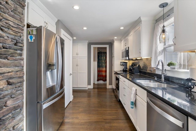 kitchen featuring a sink, tasteful backsplash, dark wood finished floors, stainless steel appliances, and dark stone counters