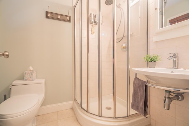 full bath featuring tile patterned flooring, baseboards, toilet, a stall shower, and tile walls