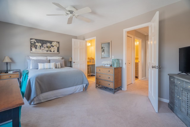 bedroom with baseboards, light colored carpet, ceiling fan, and ensuite bathroom