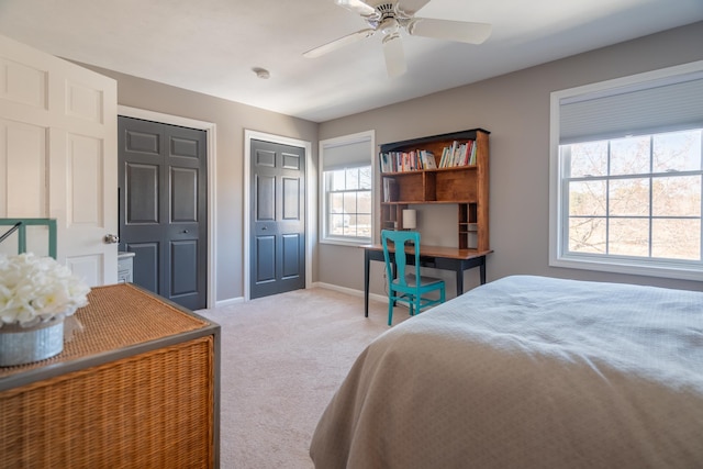 carpeted bedroom featuring a ceiling fan, baseboards, and multiple closets