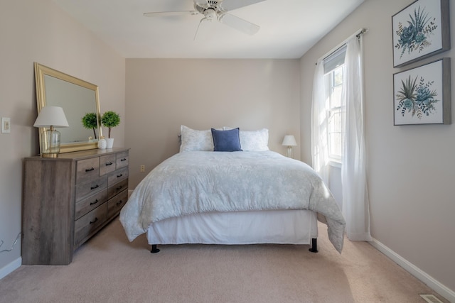 bedroom with a ceiling fan, baseboards, and light carpet