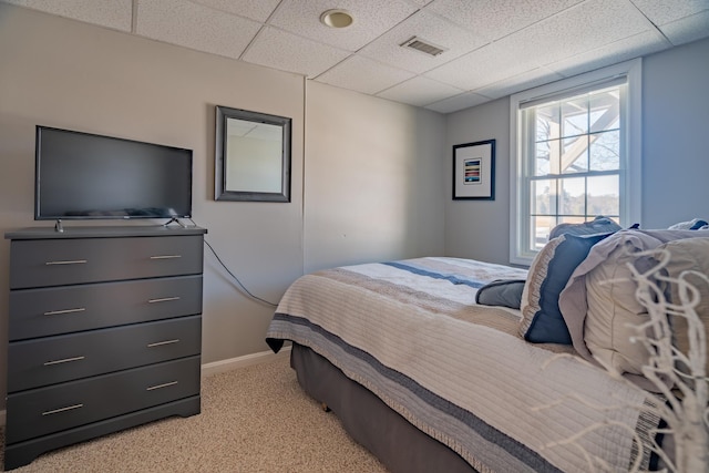 bedroom with light colored carpet, a paneled ceiling, visible vents, and baseboards