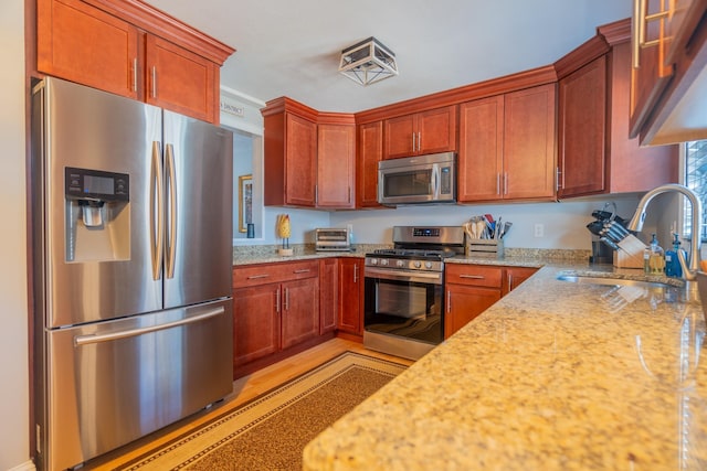 kitchen with a sink, light stone counters, visible vents, and stainless steel appliances