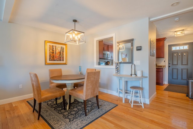 dining room with baseboards, an inviting chandelier, and light wood-style flooring