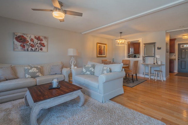 living room with light wood-style flooring, baseboards, and ceiling fan