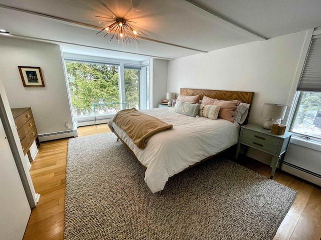 bedroom featuring light wood finished floors, a notable chandelier, and a baseboard radiator