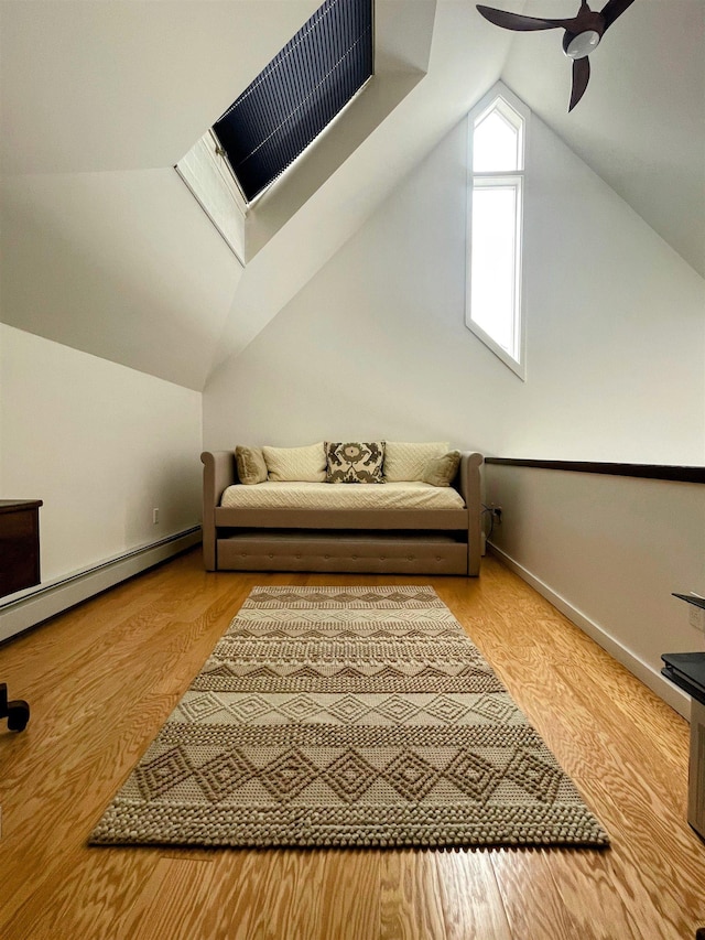 living area with ceiling fan, baseboards, lofted ceiling with skylight, wood finished floors, and a baseboard radiator