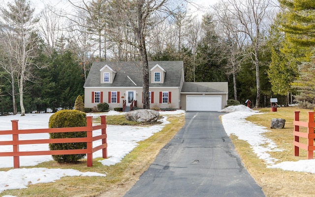 new england style home with aphalt driveway, fence, and a garage