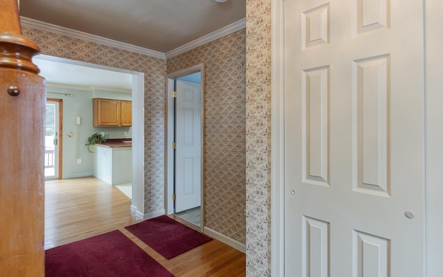 hallway with baseboards, light wood-style floors, crown molding, and wallpapered walls