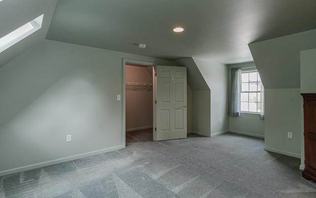 additional living space with baseboards, carpet, and lofted ceiling with skylight