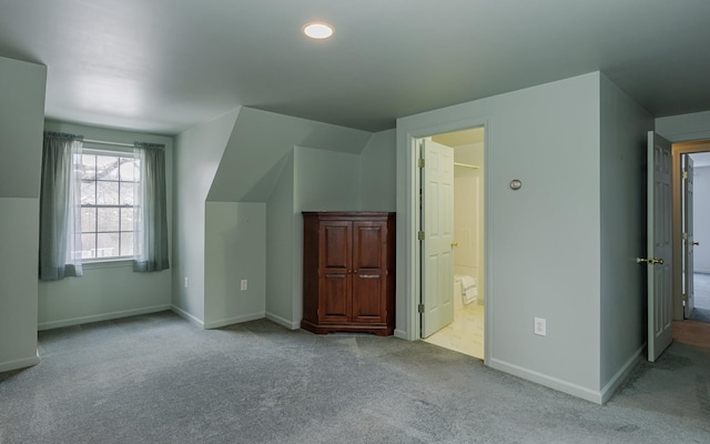 additional living space featuring baseboards, carpet floors, and vaulted ceiling