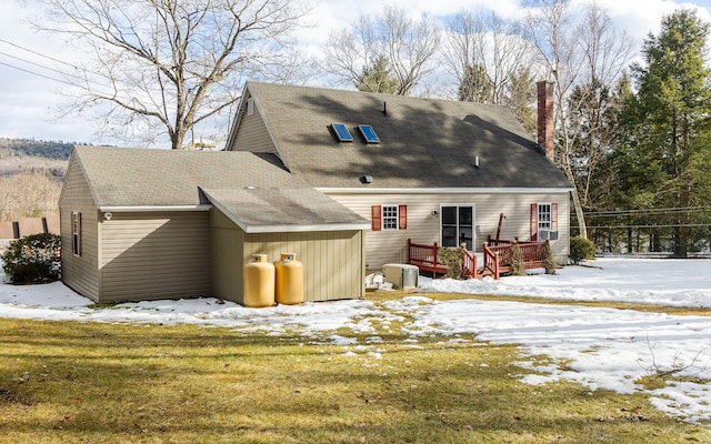 snow covered back of property with central air condition unit and a deck