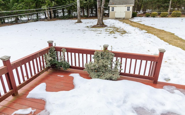 snow covered deck featuring an outbuilding and a storage unit